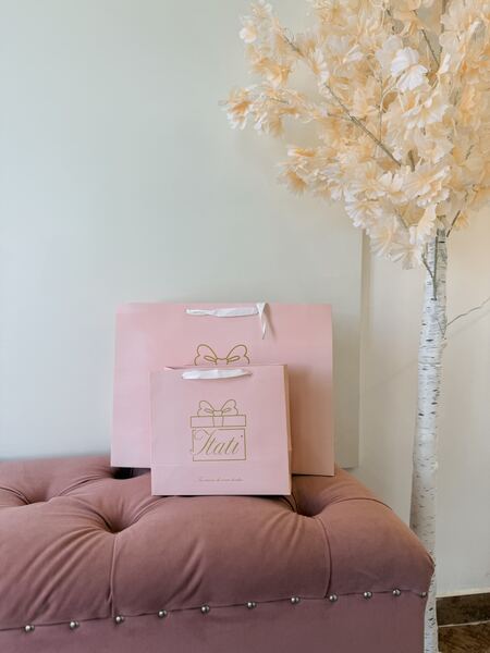Bolsas de regalo Itati sobre sillón rosa, decoración floral